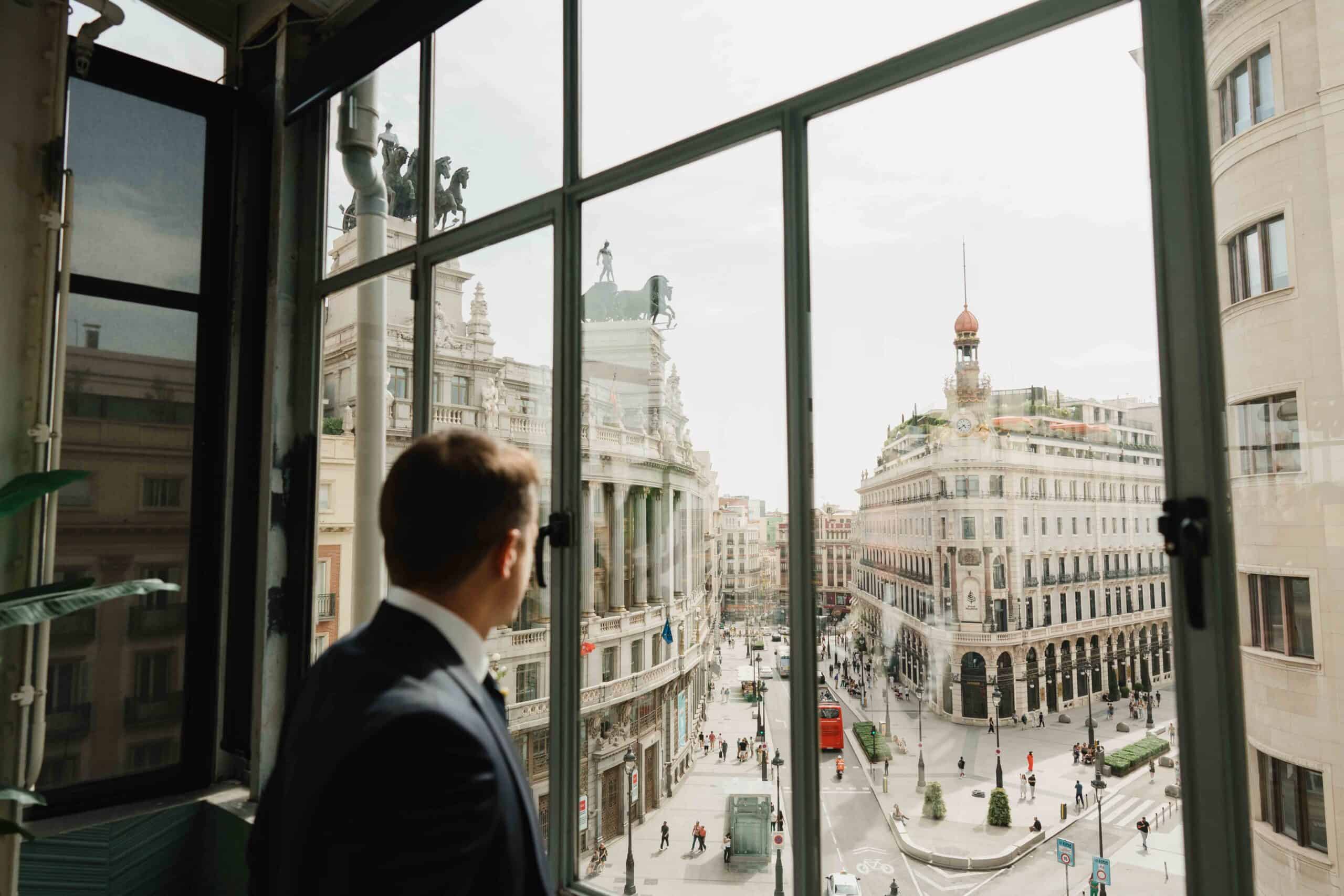 Editorial groom portrait on a Madrid balcony — luxury wedding photography by Estudio Zoe