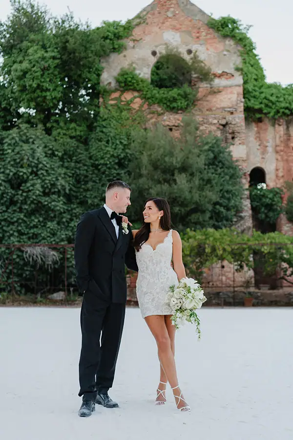 Bride and groom posing in front of ivy-covered historic ruins