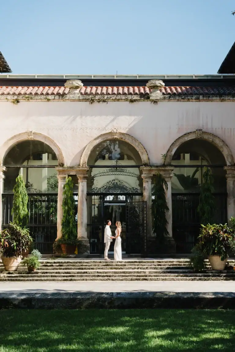 Gabby and Mike standing by the arched facade at Vizcaya Museum and Gardens in Miami