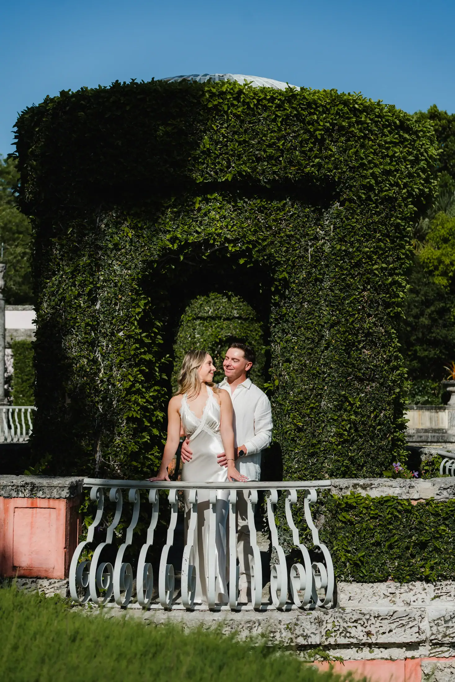 Gabby and Mike photographed under a green arch during their Vizcaya engagement session