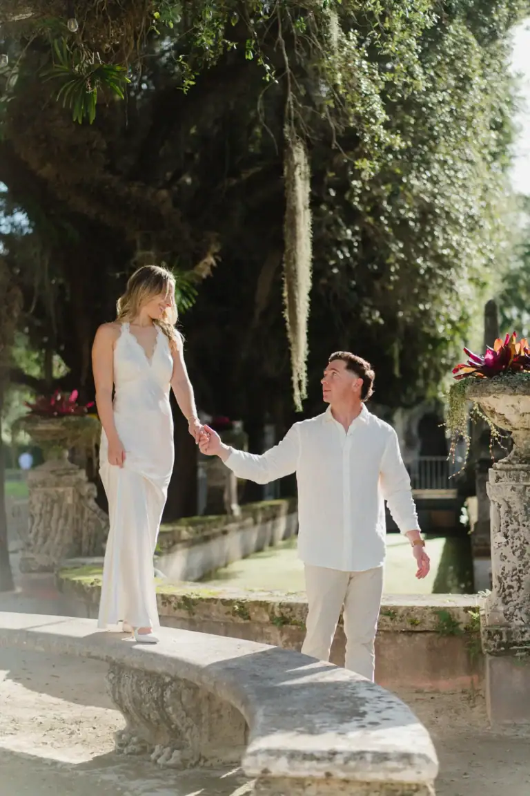 Gabby and Mike holding hands near the waterfront gardens at Vizcaya in Miami